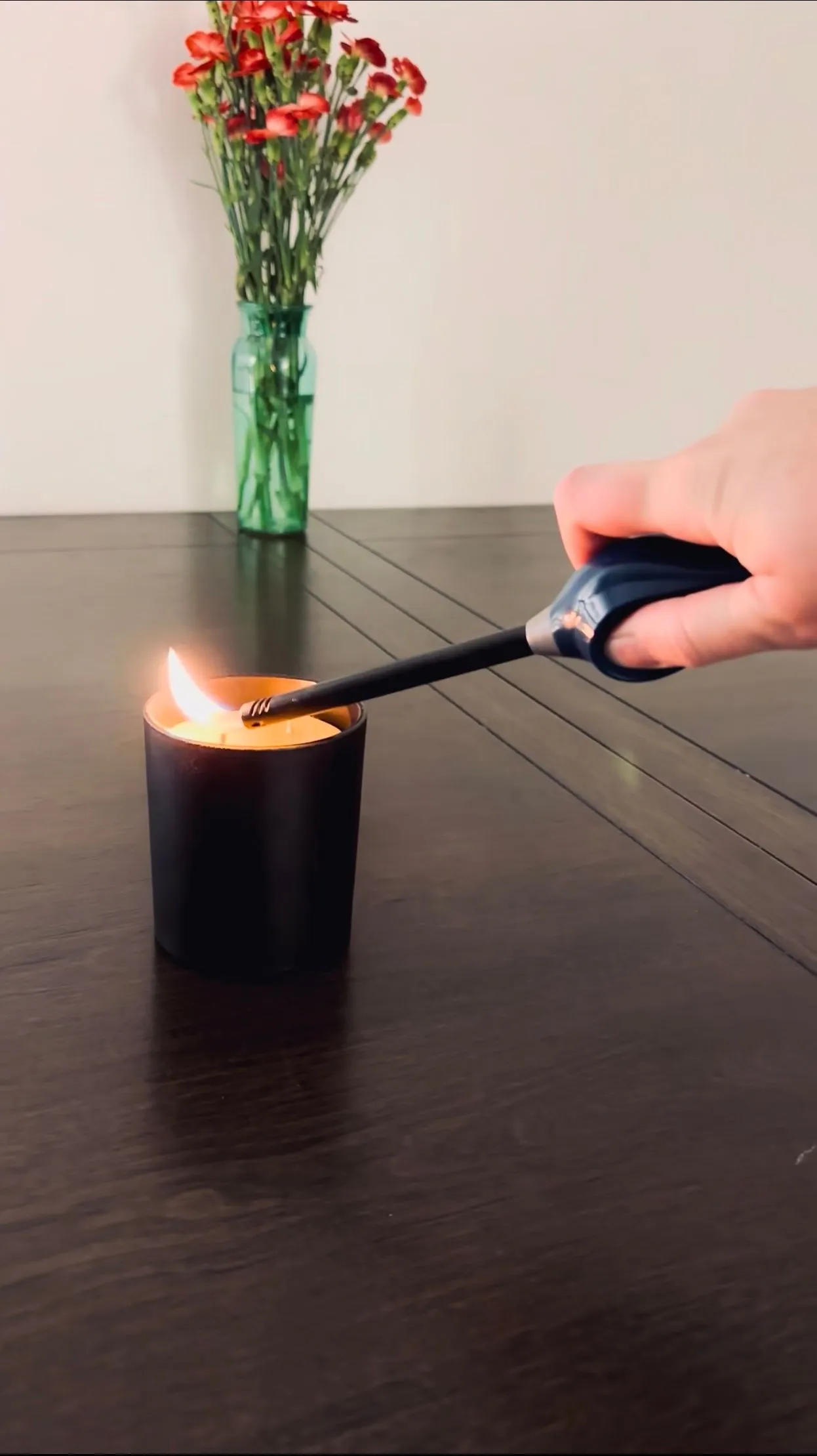 Lighting a beeswax candle in a black glass jar